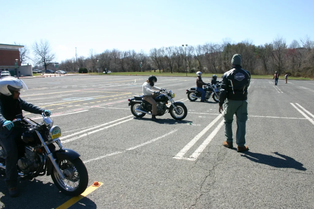 Motorcycle safety instructor supervising students practicing riding skills on a training course.