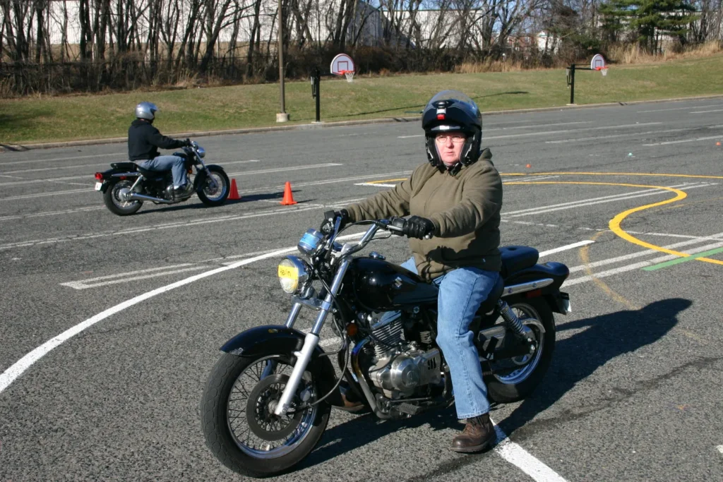 Motorcycle safety training session with riders practicing handling skills in a parking lot course.