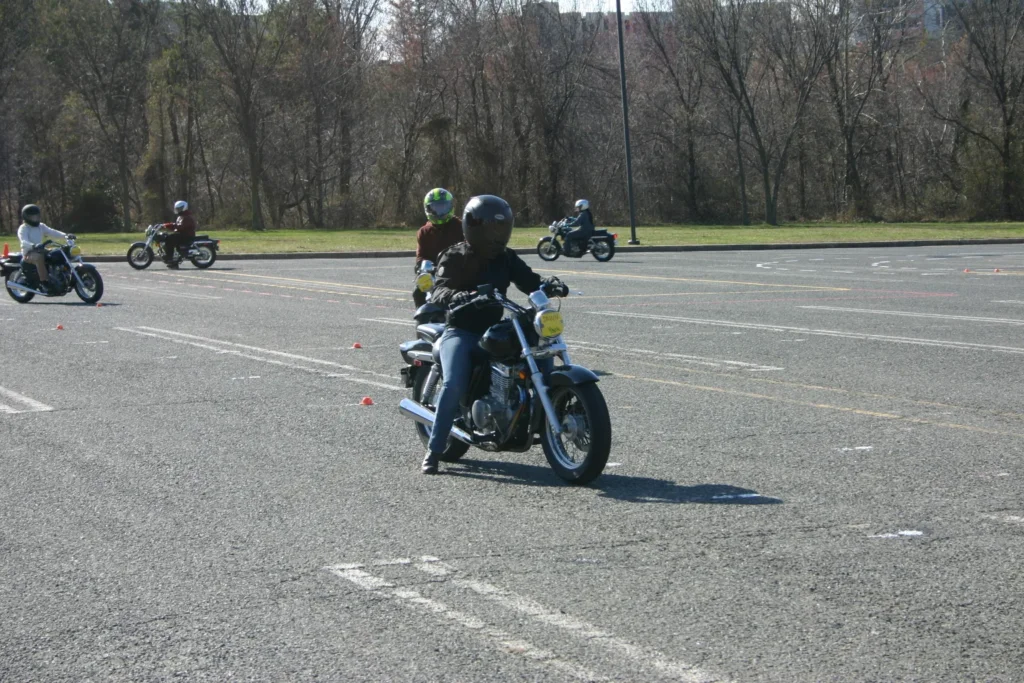 Group of motorcycle riders practicing safety skills and maneuvering through cones on a training course.